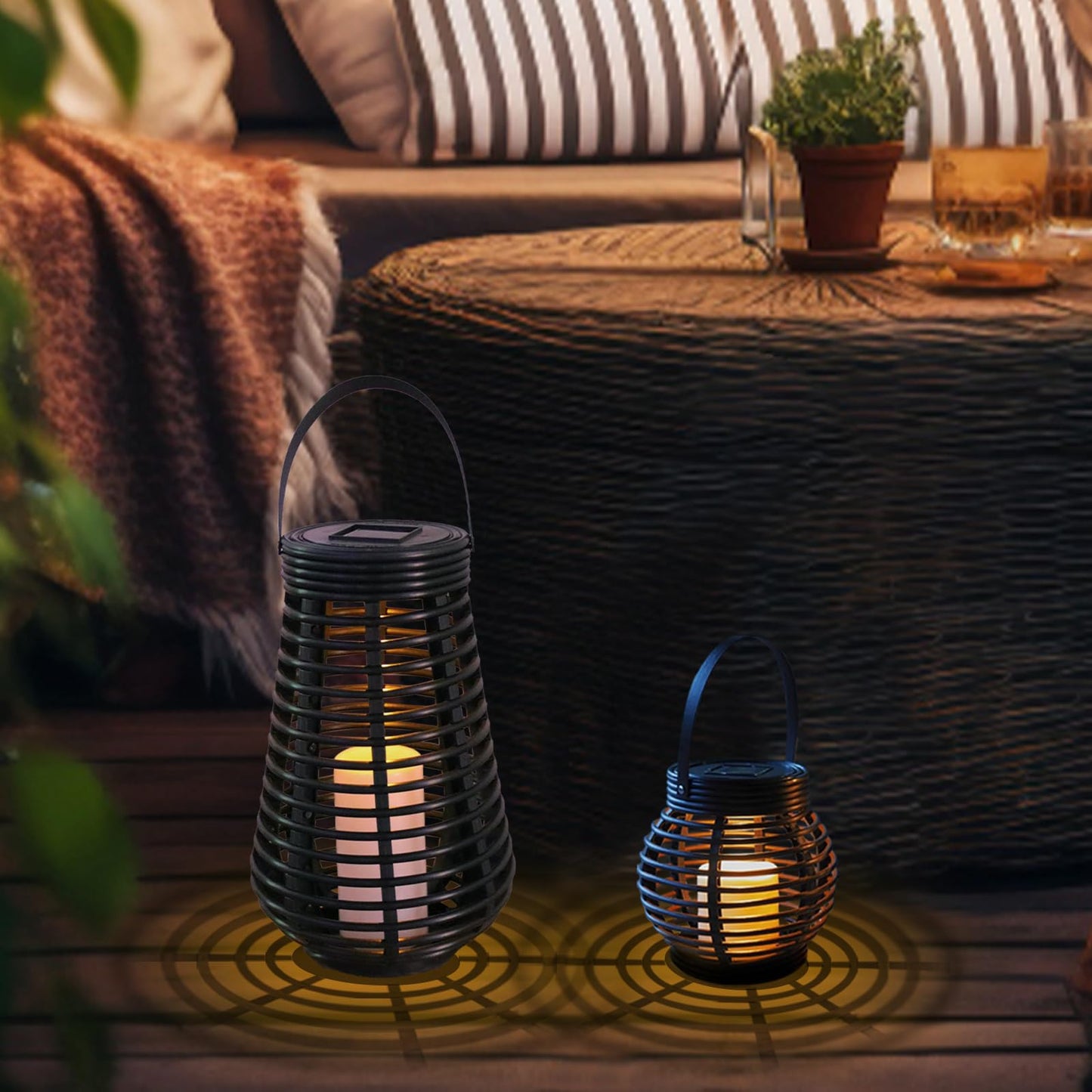 Zwei schwarze Solarlaternen mit warmweißem Licht und Rattanoptik auf Terrasse